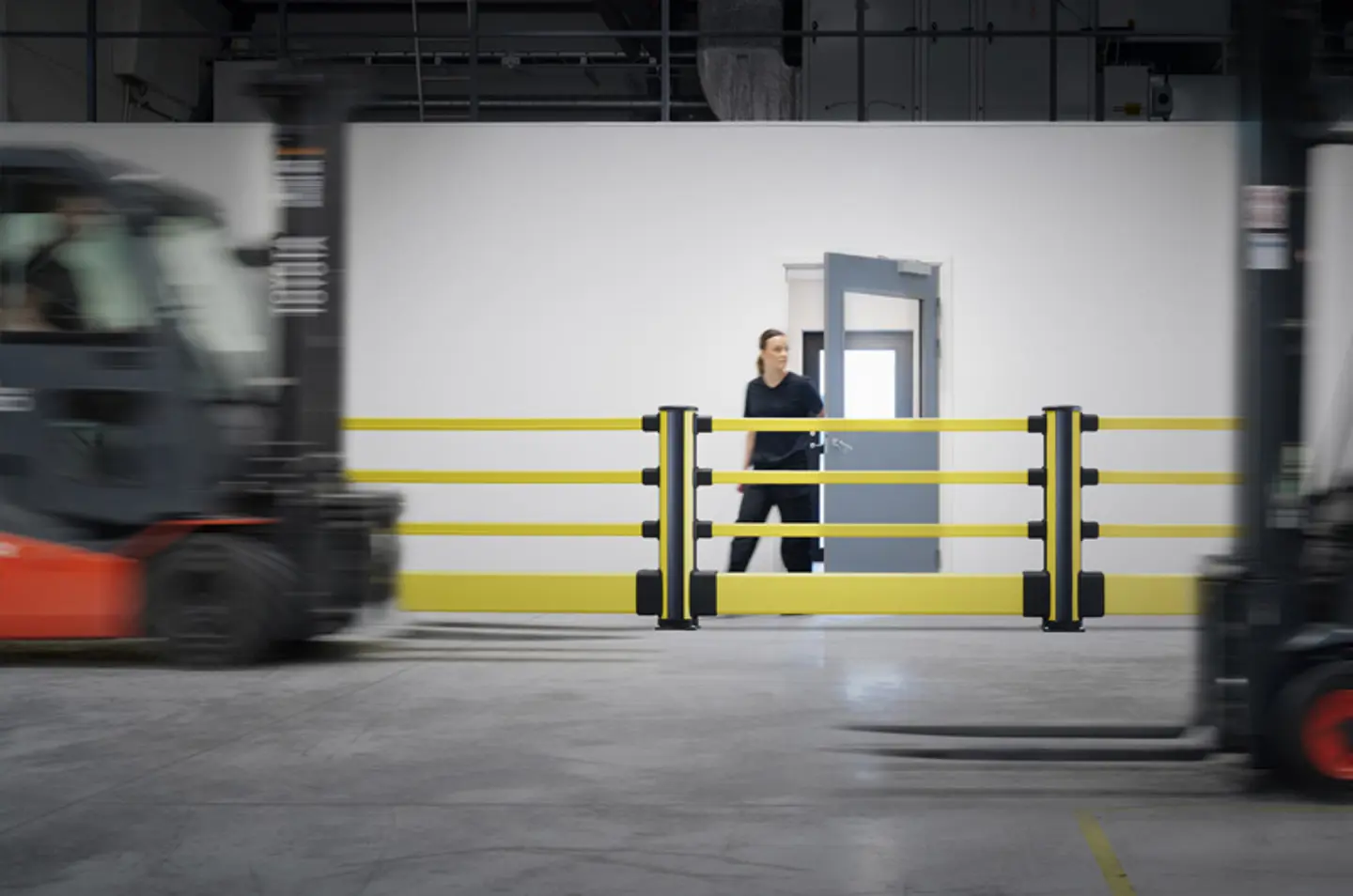 Pedestrian shown behind Axelent impact barriers with forklift moving past in the foreground