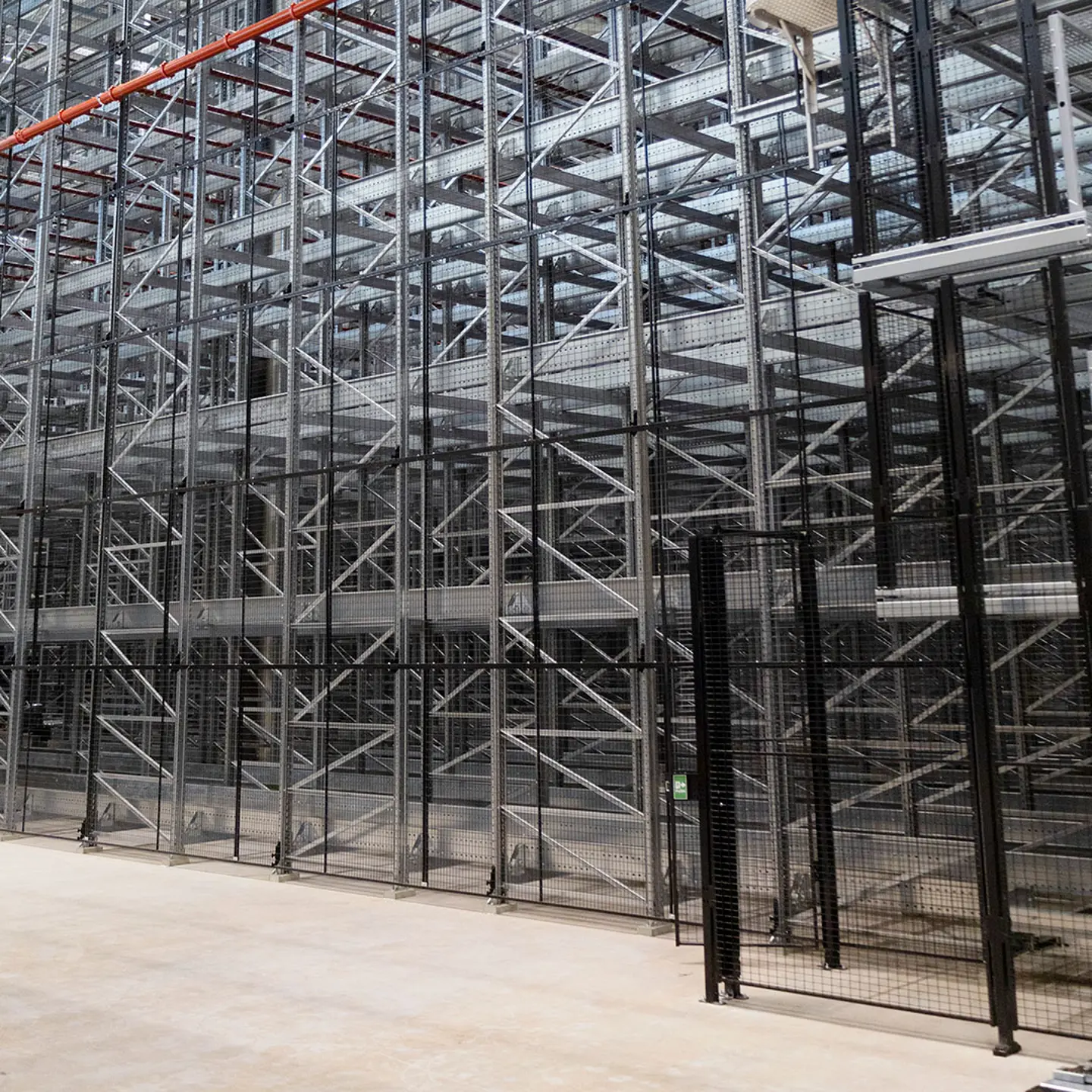 An automated storage pallet racking system is shown guarded with safety fencing and a door