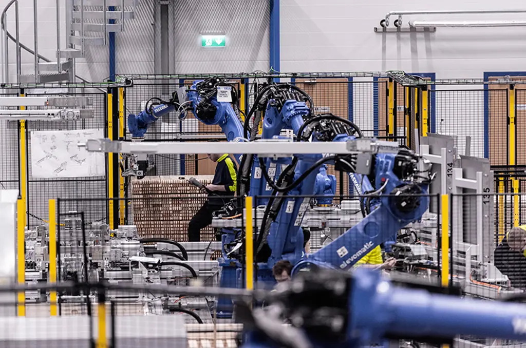 Robotic arms palletizing cartons inside safeguarded automation cell