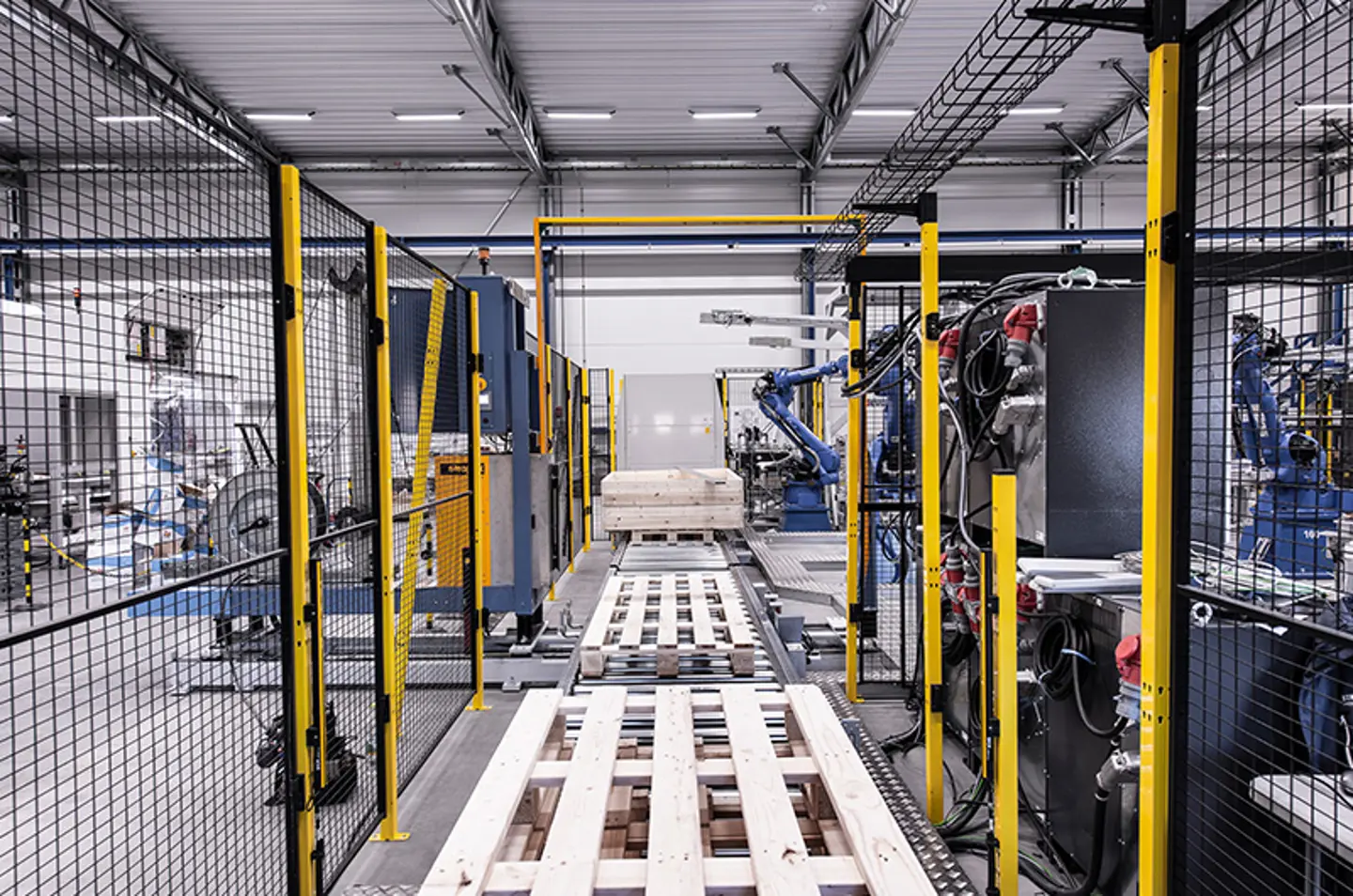 Robotic arms palletizing cartons inside safeguarded automation cell